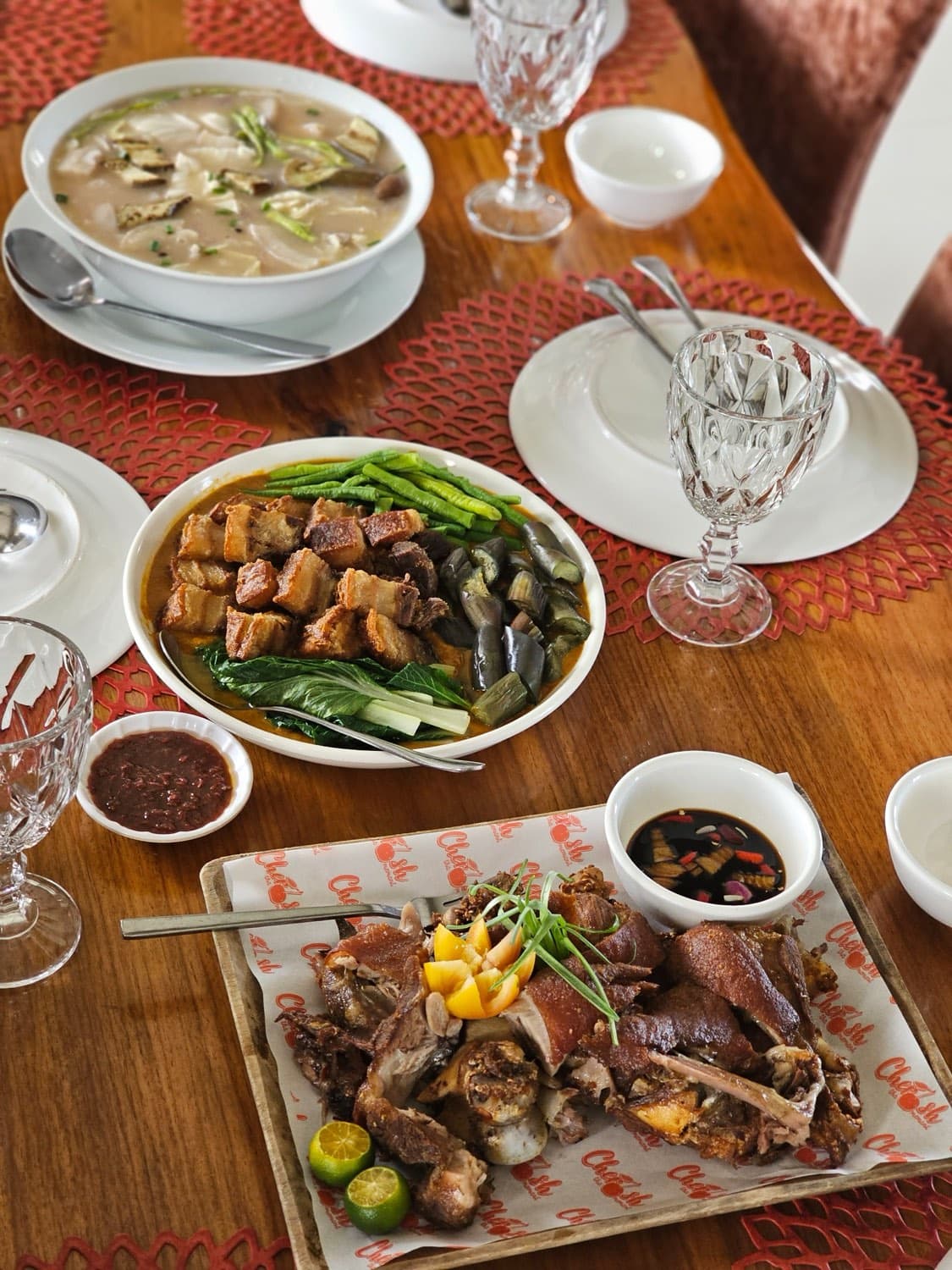 A shared table of Filipino dishes at Cherish Resort — crispy pata, kare-kare, and soup